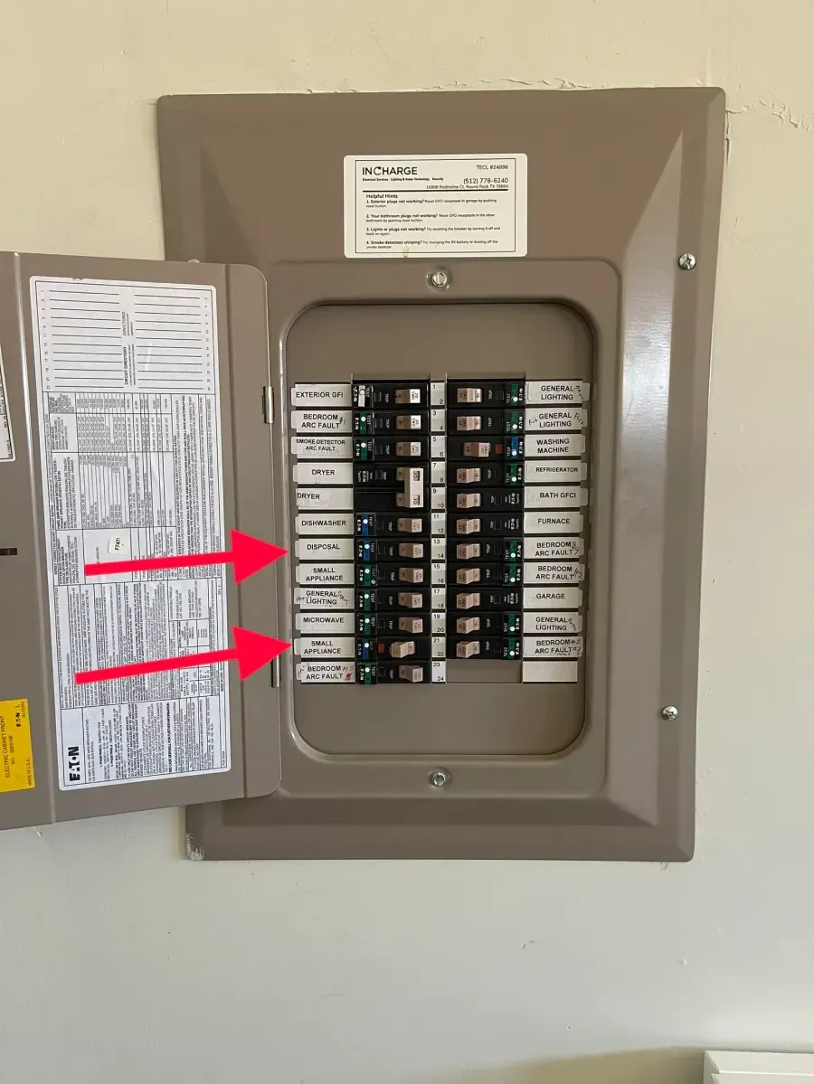 Open electrical breaker panel with circuit labels and two red arrows pointing to switches