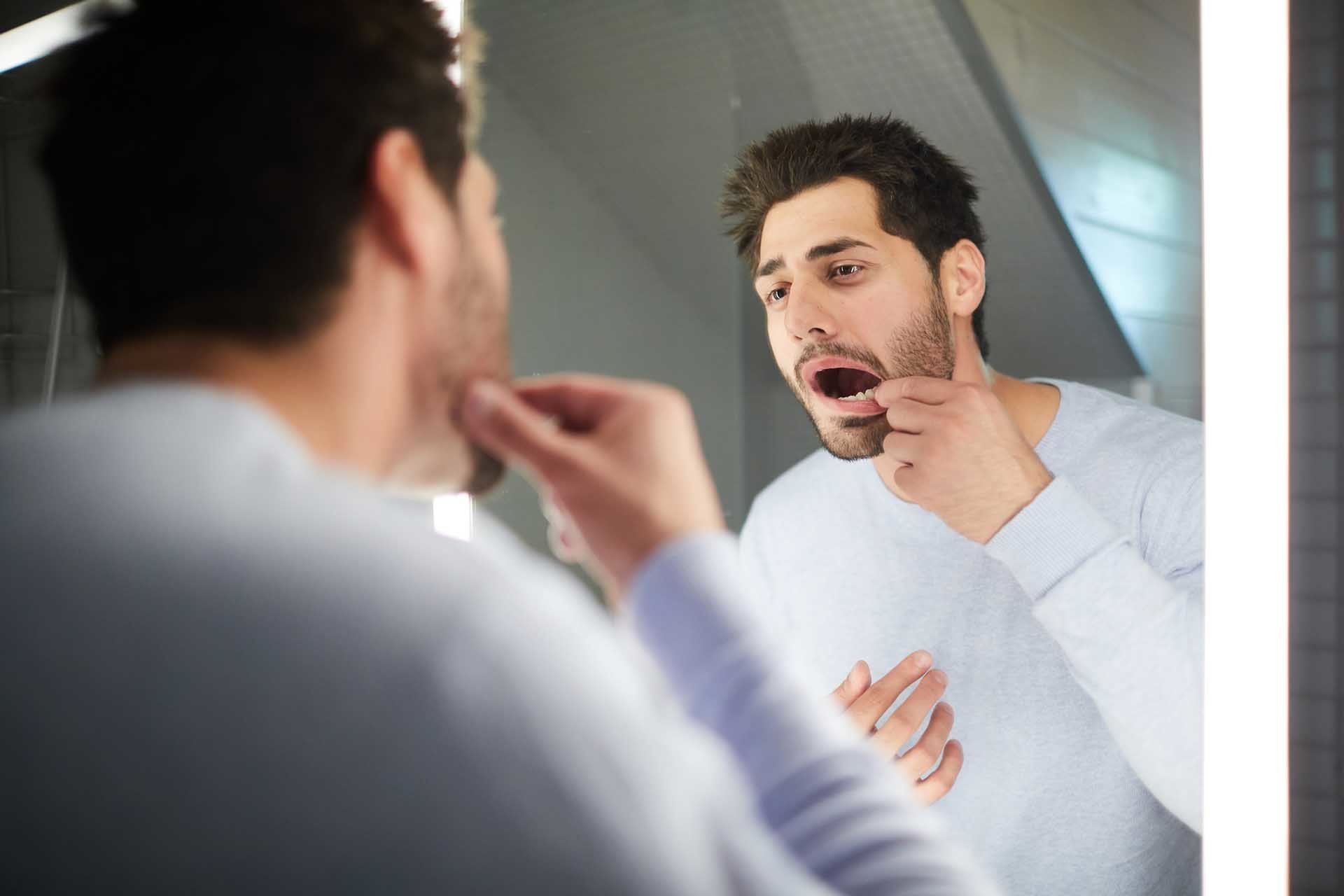 Man Checking His Tooth in The Mirror — Statesville, NC — Joseph M. Perry, D.D.S., P.A.