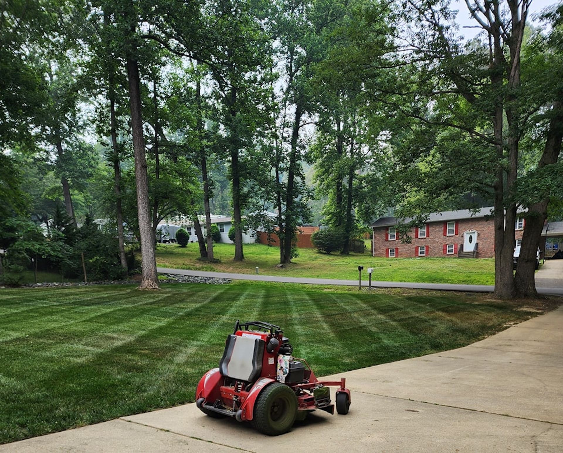 A red lawn mower is cutting a lush green lawn.