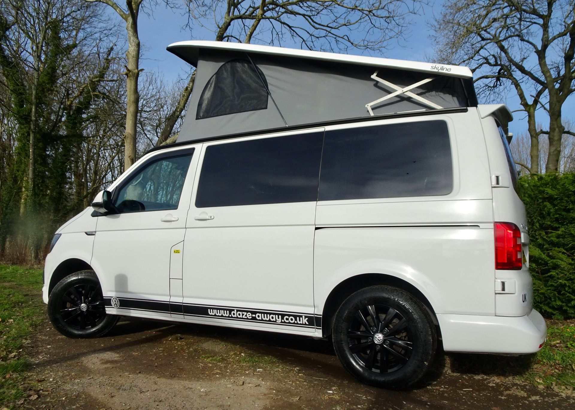 a white van with a pop top roof is parked in a field .