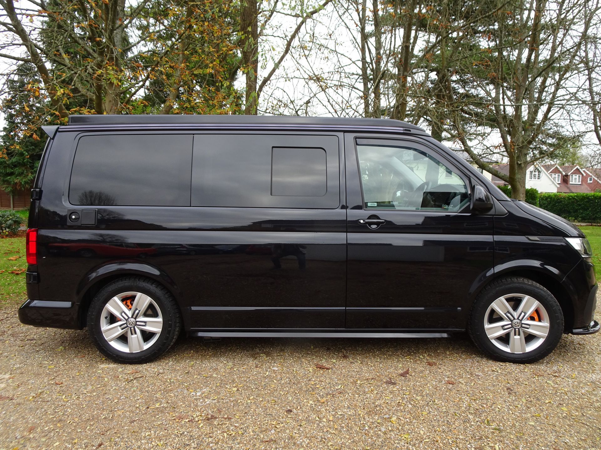 A black van is parked on a gravel road.
