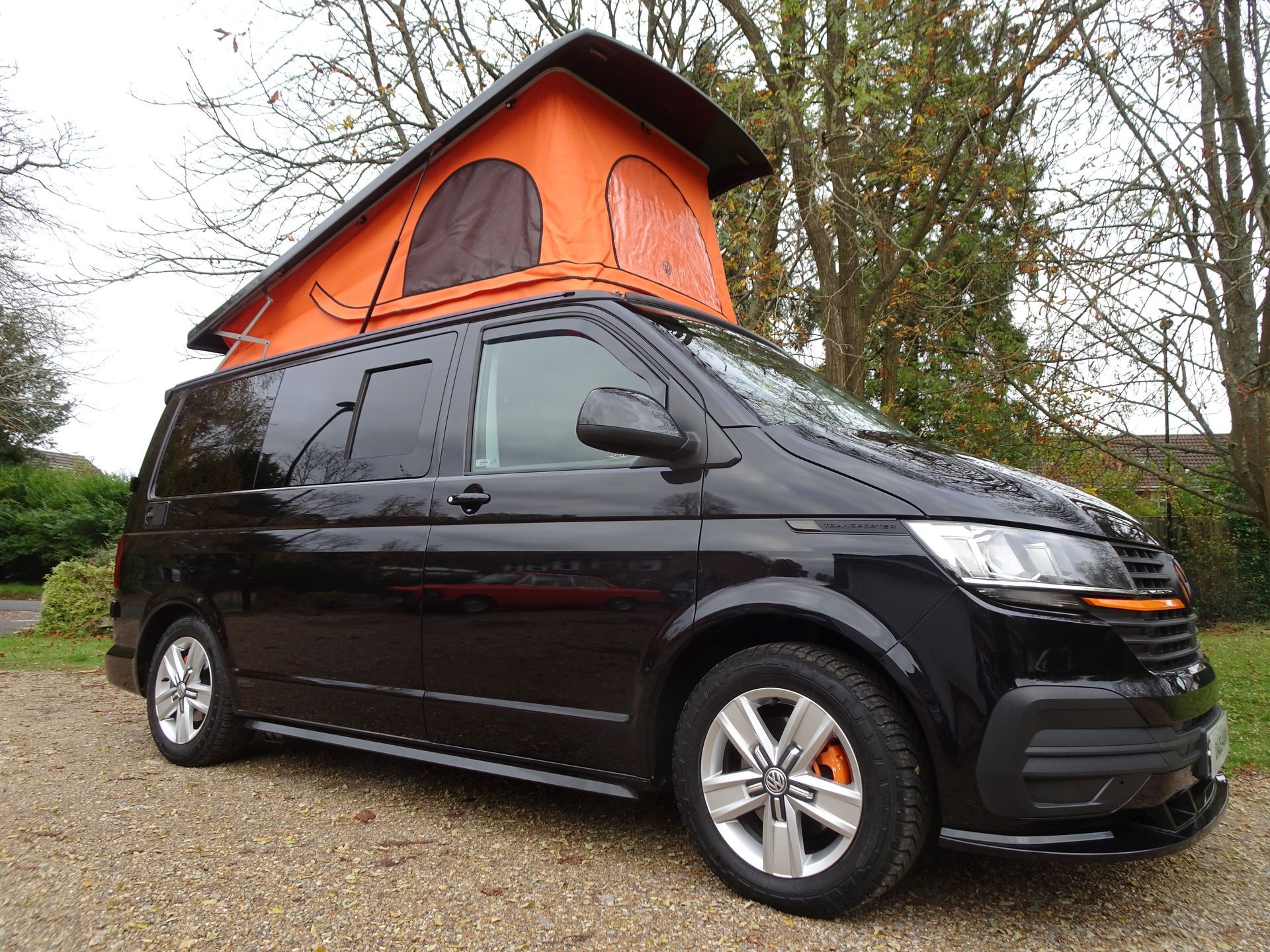 A black van with an orange tent on top of it.