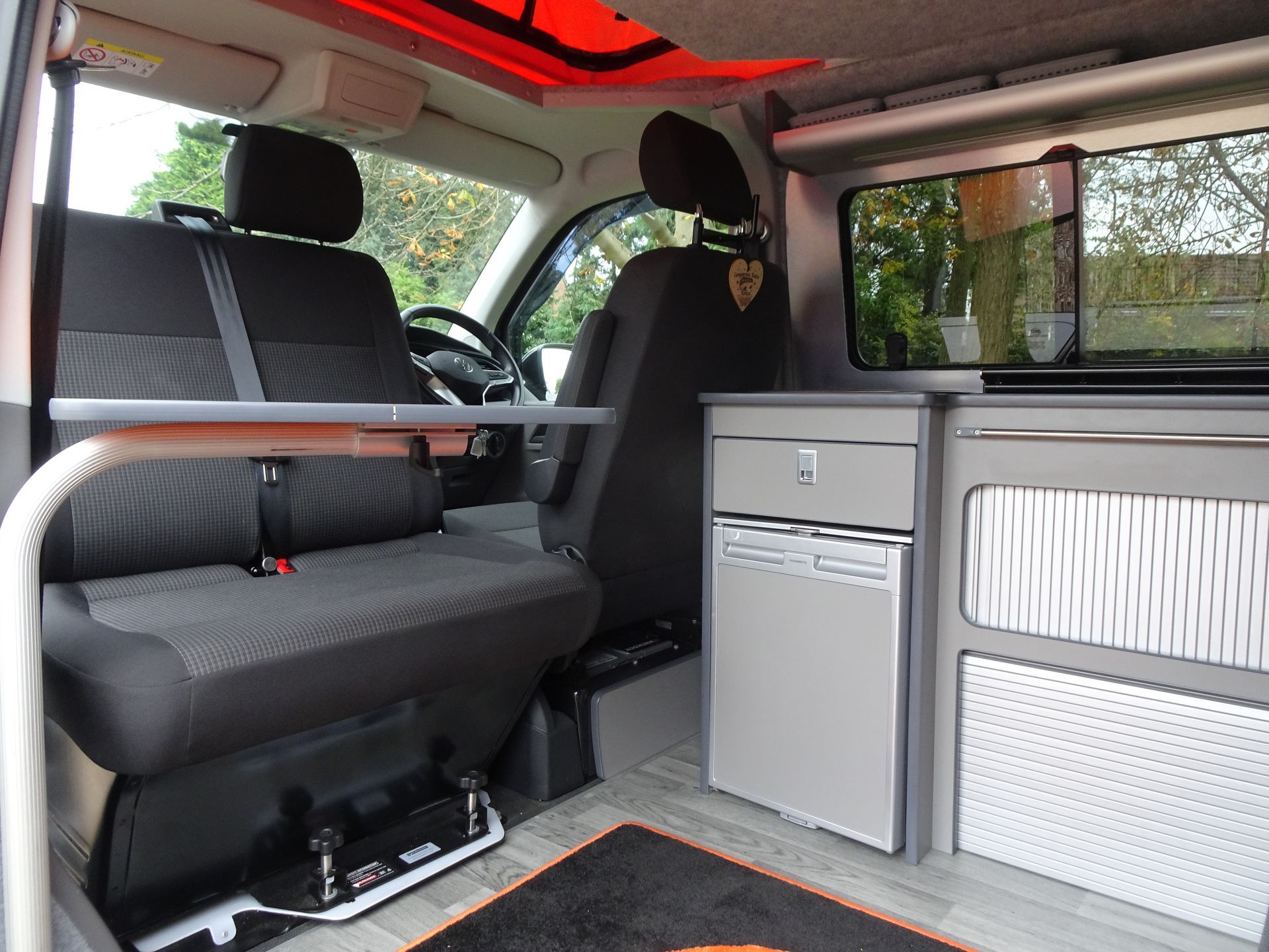 The inside of a van with a table and a refrigerator.