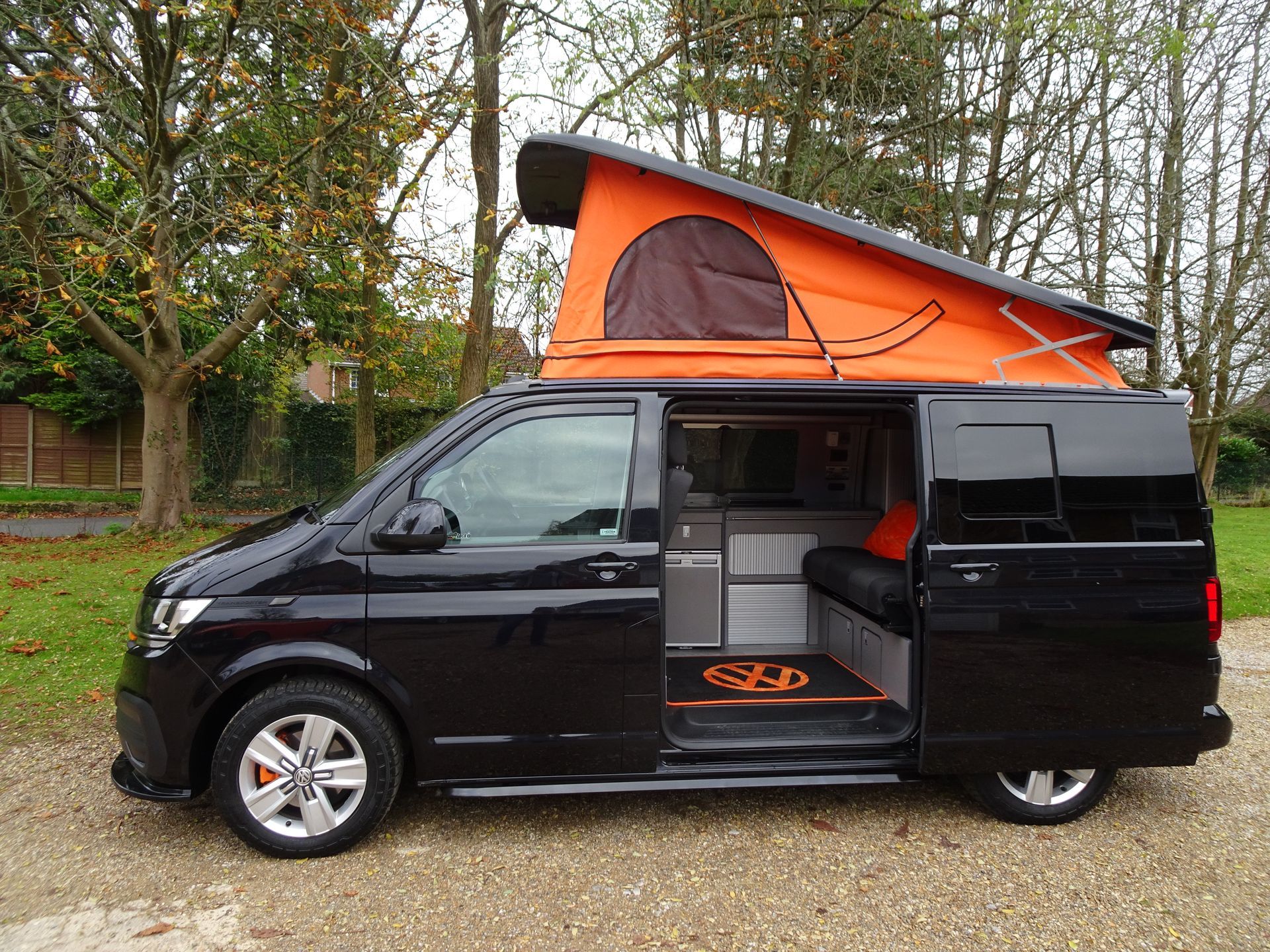 A black van with an orange roof is parked in a parking lot.