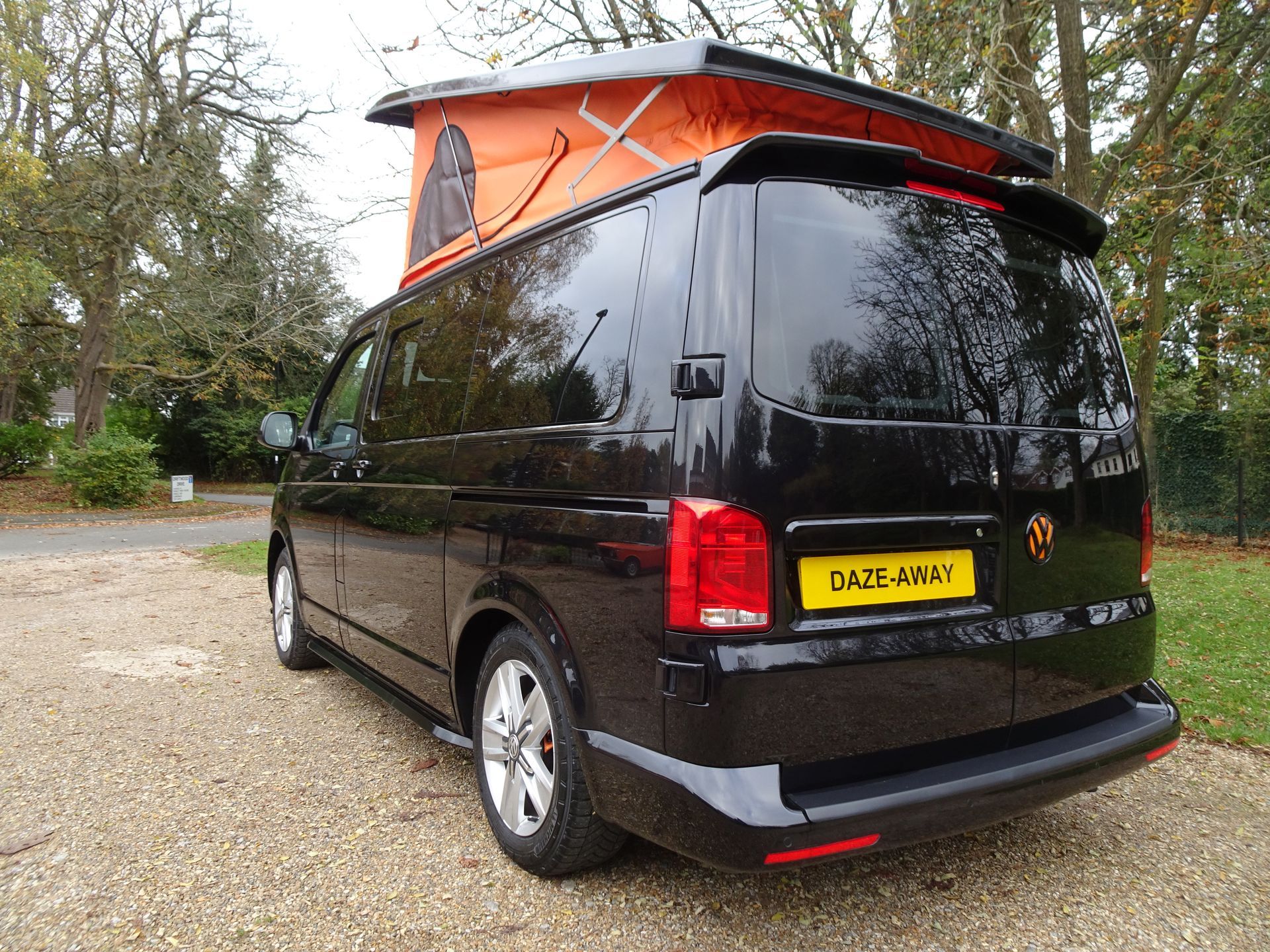 A black van with an orange roof is parked on the side of the road.