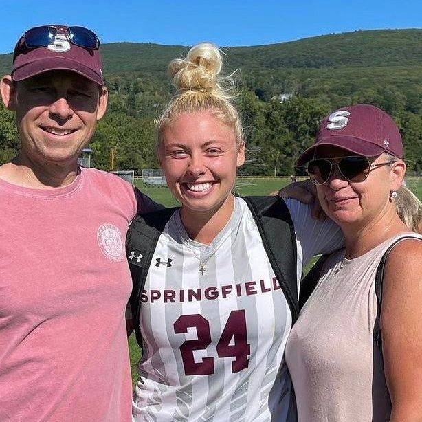 A girl wearing a jersey with the number 24 is posing for a picture with her parents.