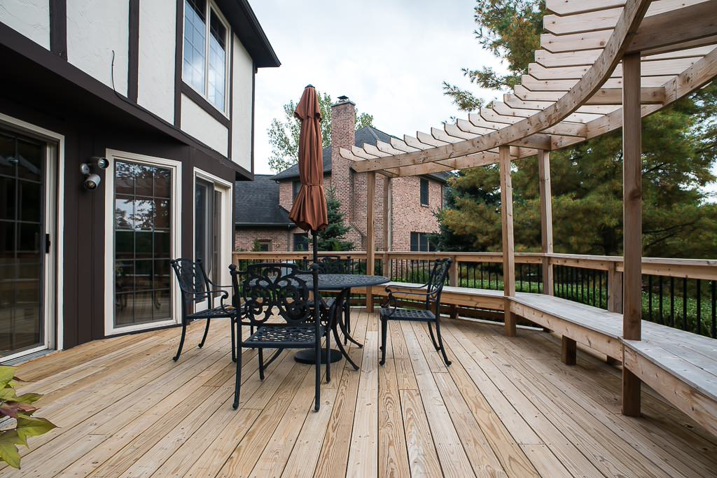 Screened-in backyard pool with blue water, wooden deck, and lounge chairs in the sun