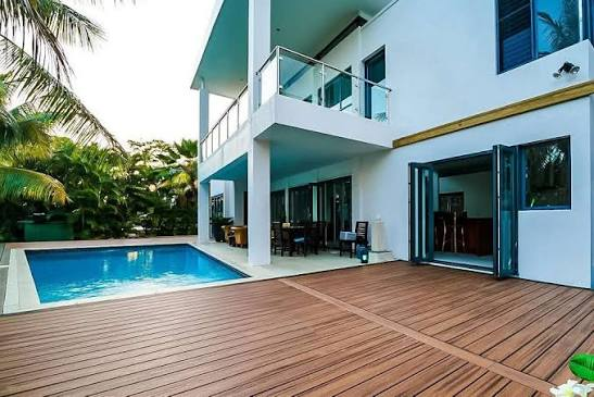 A screened in porch with a couch and ottoman and a view of a pool.