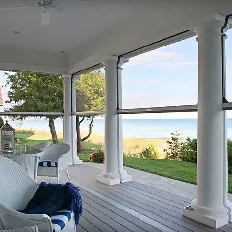 A screened in porch with a brick house in the background.