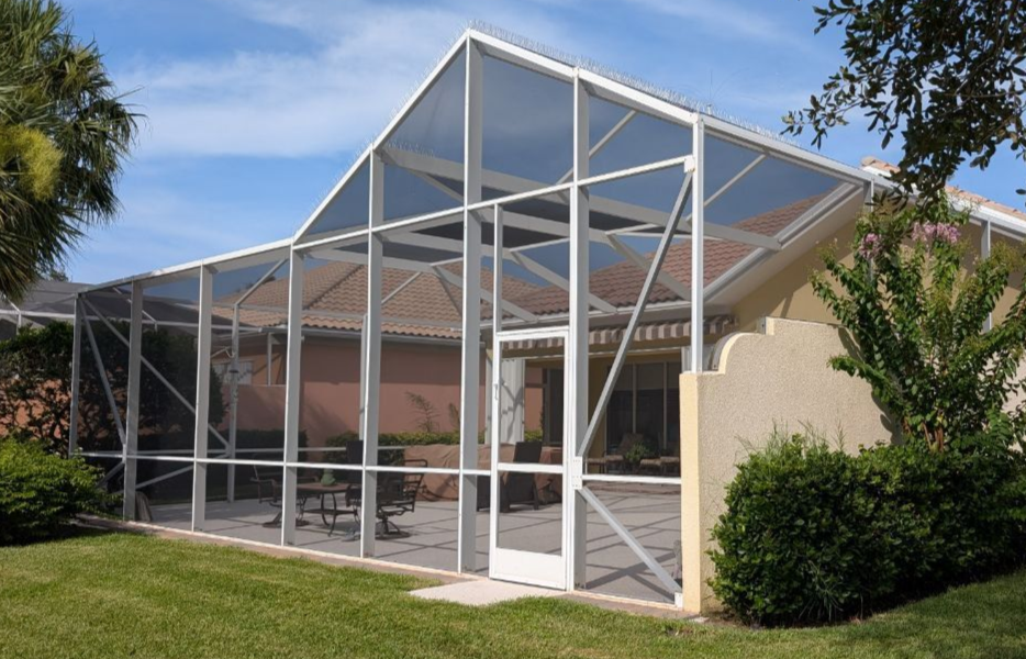 There is a swimming pool in the backyard of a house with a screened in area.