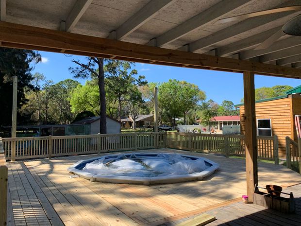A screened in porch with a brick house in the background.