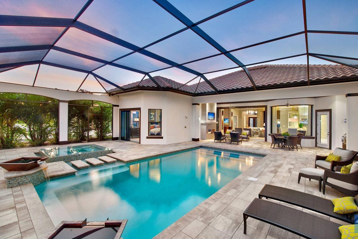 There is a swimming pool in the backyard of a house with a screened in area.