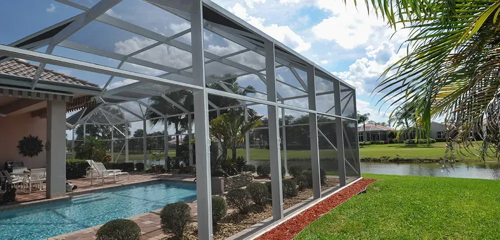 A screened in porch with a swimming pool in the background