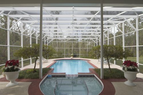 A screened in porch with a swimming pool in the background