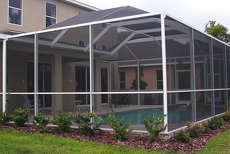 A screened in porch with a swimming pool in the background