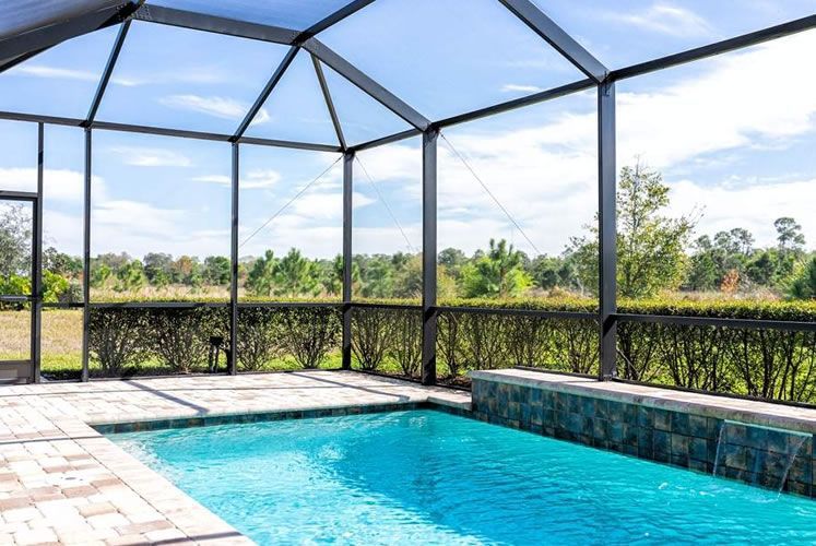 There is a swimming pool in the backyard with a screened in area.