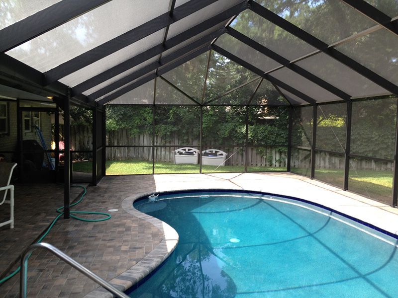 Screened-in pool area with a curved pool, and paver patio