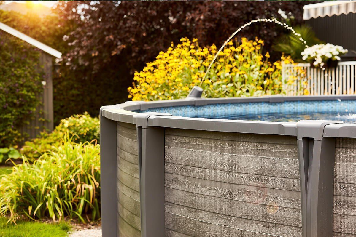 Above ground pool with a wood-grain resin wall and surrounding deck in a Titusville, Brevard County Florida backyard