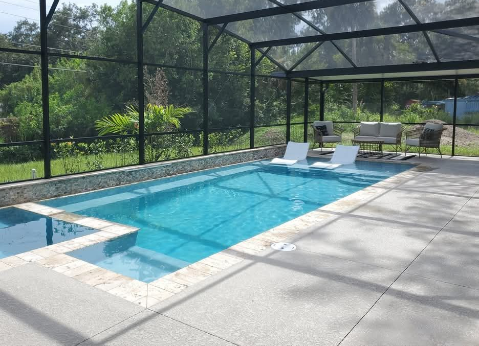 Screened backyard pool with lounge chairs and a white bench beside blue water and a patio.