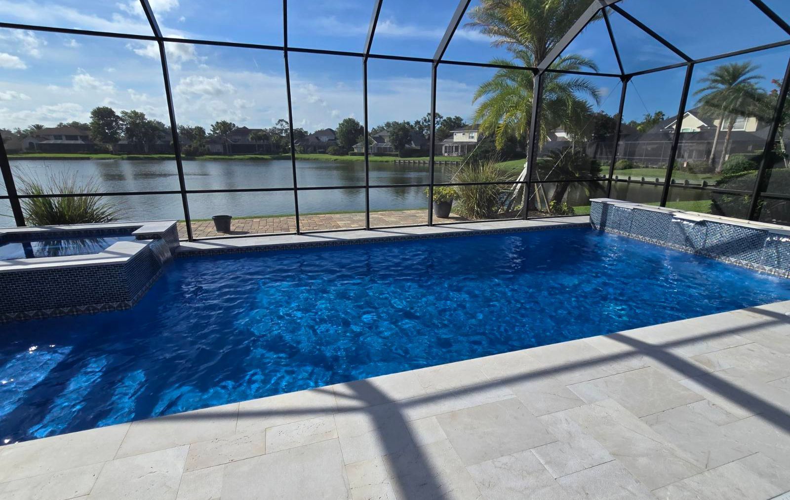 Screened-in backyard pool with blue water, patio pavers, and a lake view beyond the lanai
