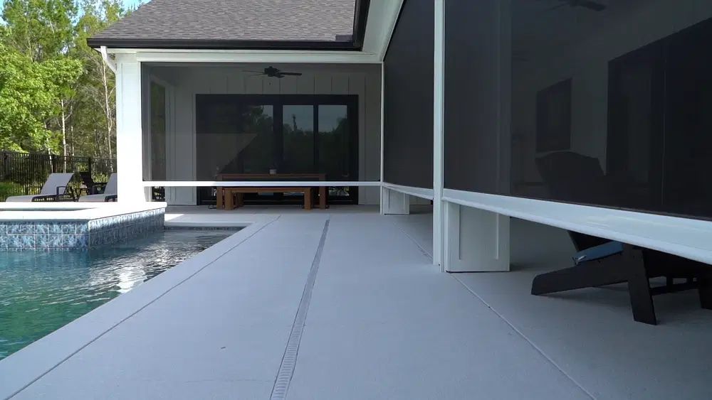 A screened in porch with a brick house in the background.