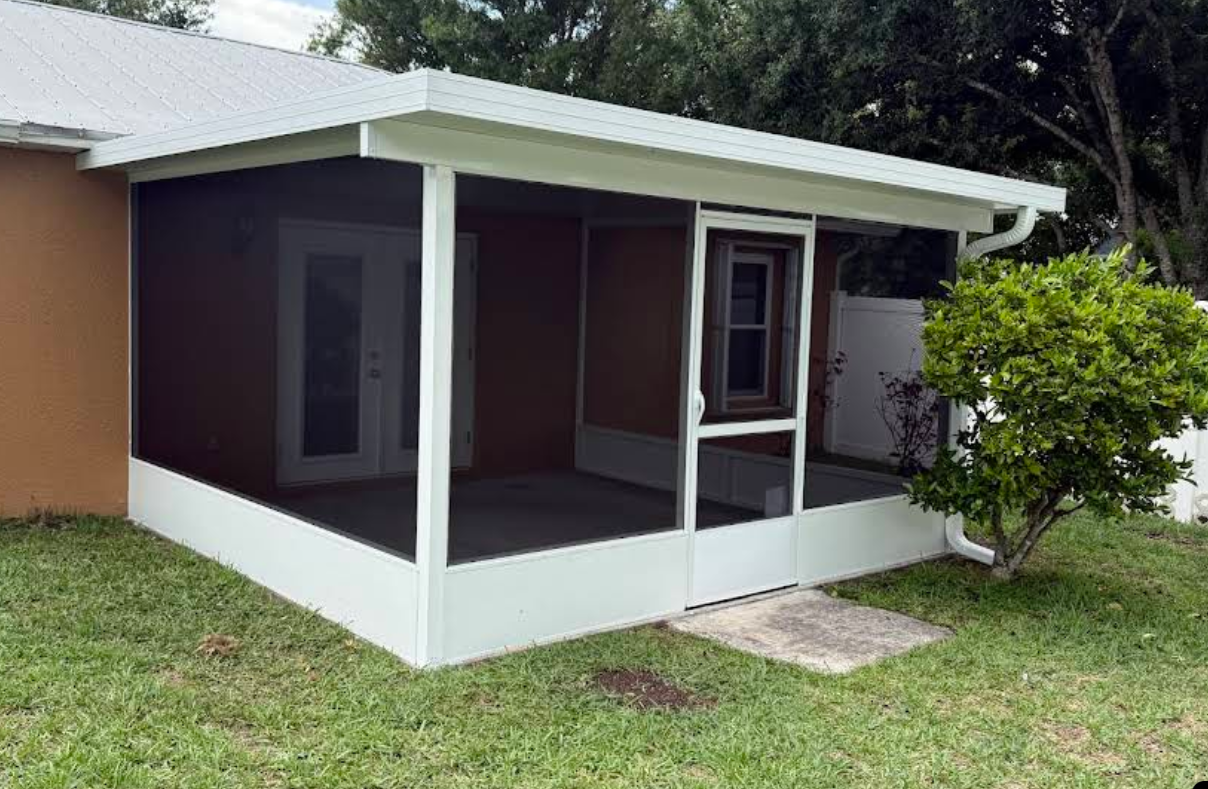 Small house porch with white roof and trim, brown walls, screened seating area, and green lawn.