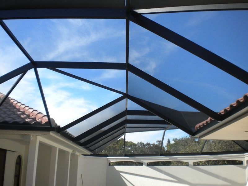 A screened in porch with a swimming pool in the background