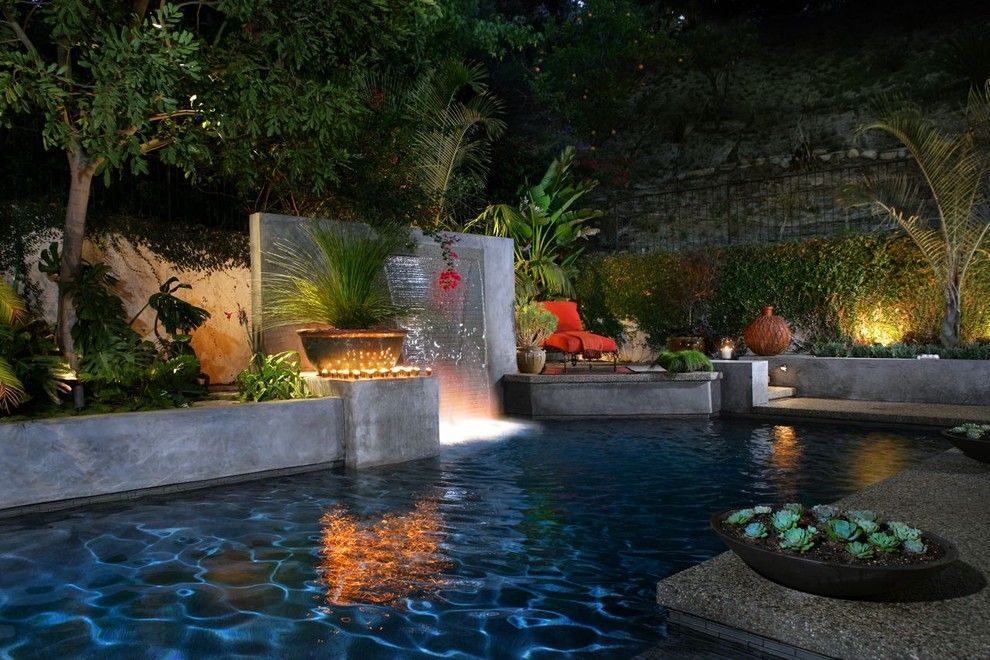There is a swimming pool in the backyard of a house with a screened in area.