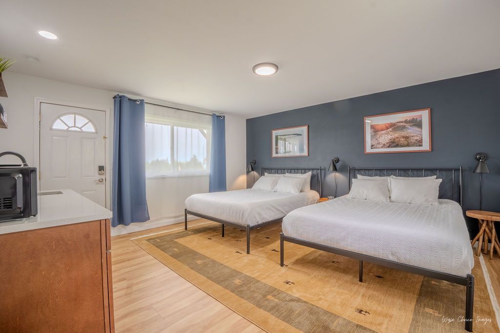 Bedroom with two beds, blue accent wall, wooden floors, and a small microwave.