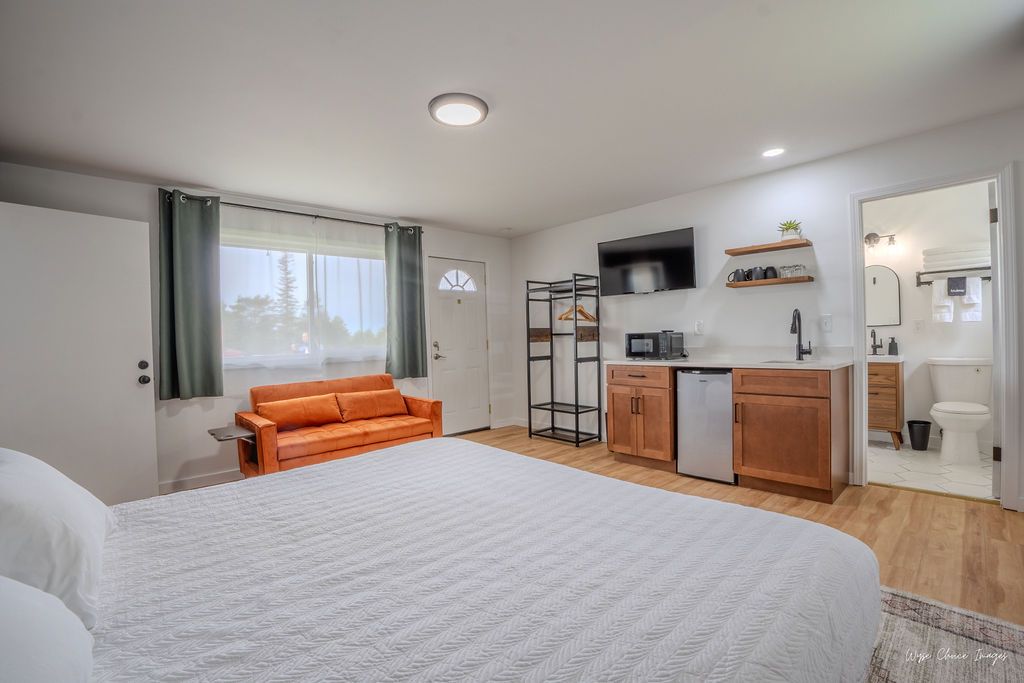 Studio apartment with bed, orange sofa, kitchenette, and bathroom visible.