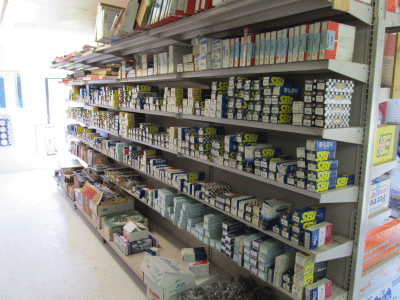 Shelves stocked with assorted hardware supplies and small boxes in a store aisle