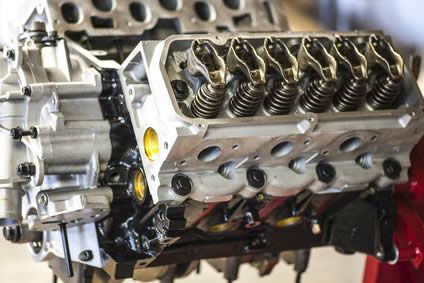 Close-up of a car engine cylinder head with exposed valves and metallic components.
