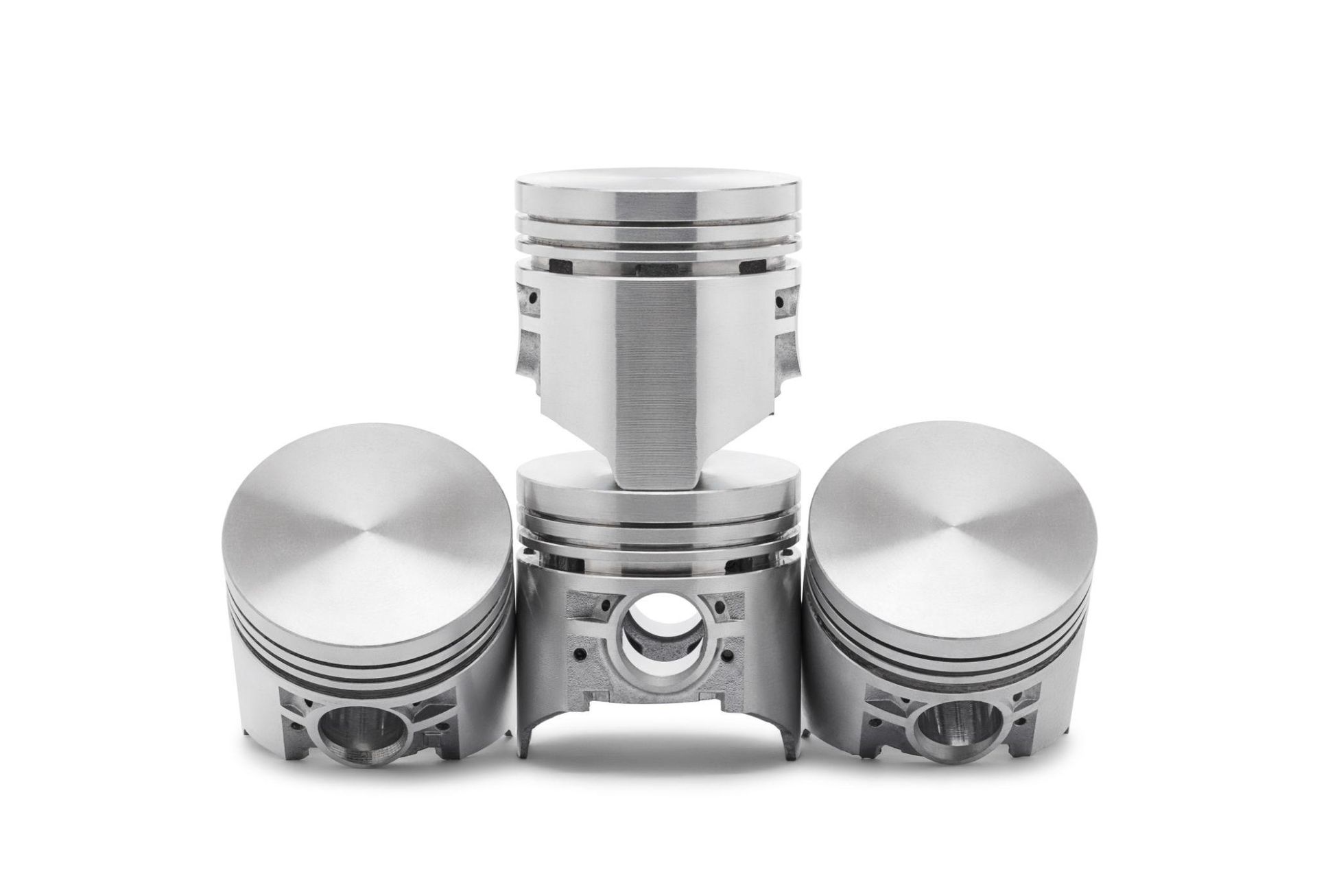 Three shiny silver engine pistons arranged in a row on a white background