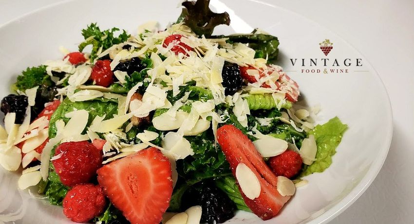 Una ensalada con fresas y almendras en un plato blanco.