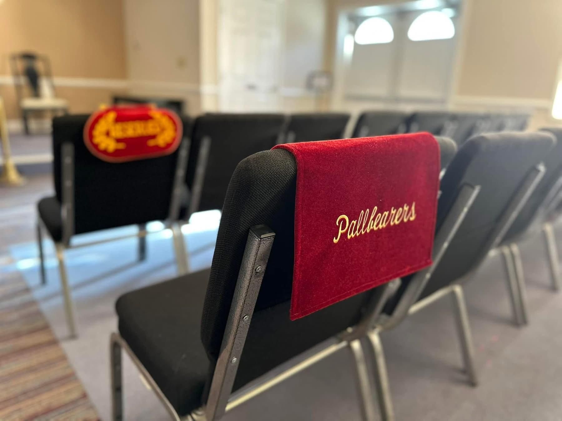 Rows of black chairs with red embroidered headrests that read 