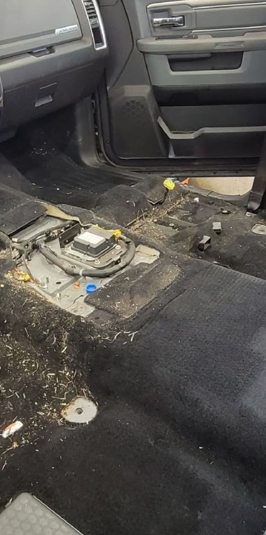 The inside of a dirty car with a fuel pump missing.