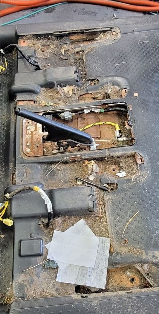 The bottom of a car with a lot of wires coming out of it.