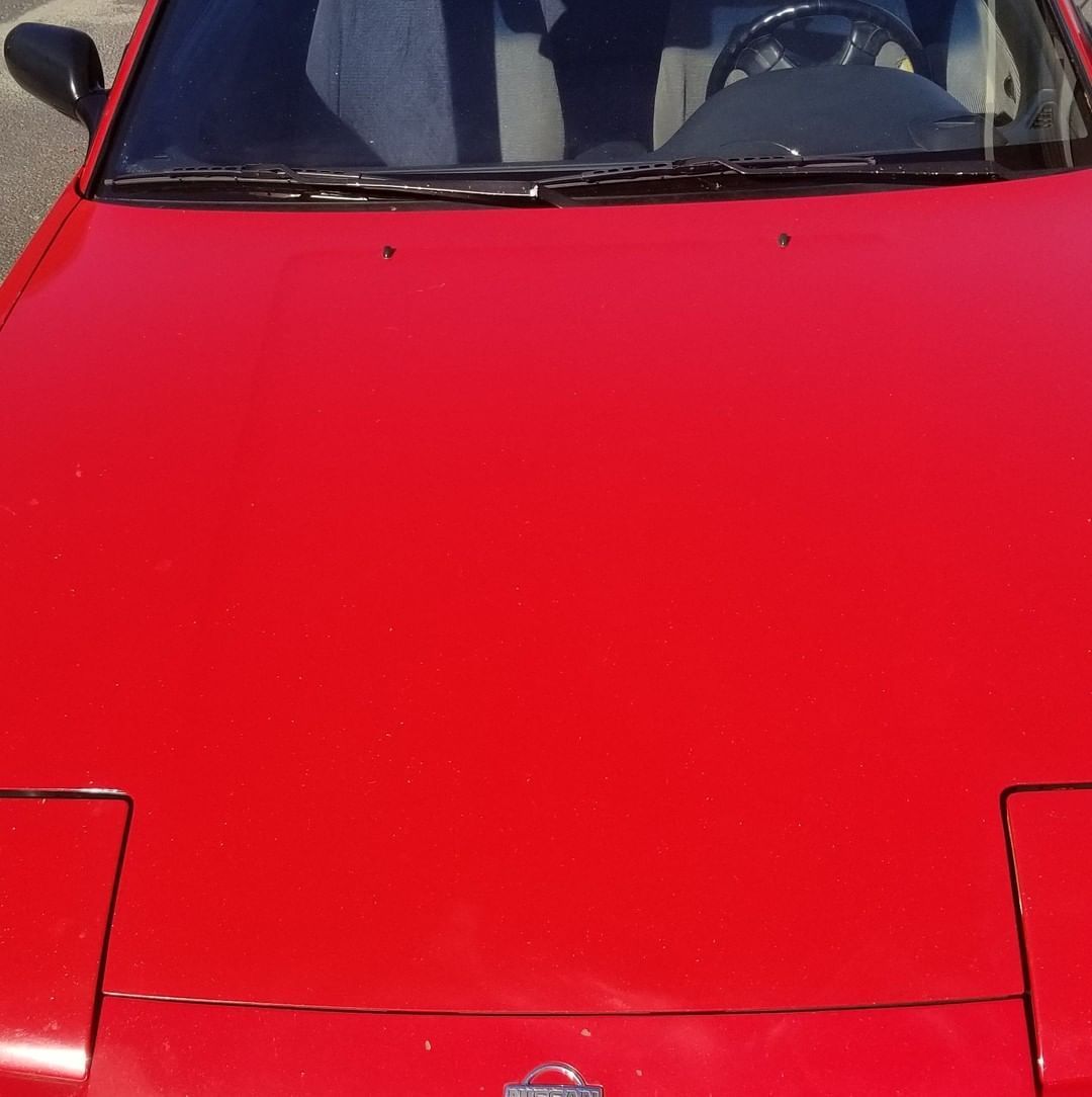 A red car with a nissan logo on the hood