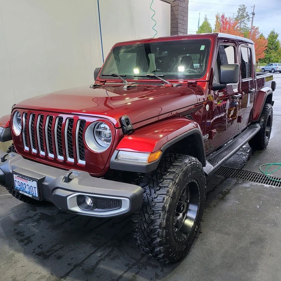 A red jeep is parked in front of a building.