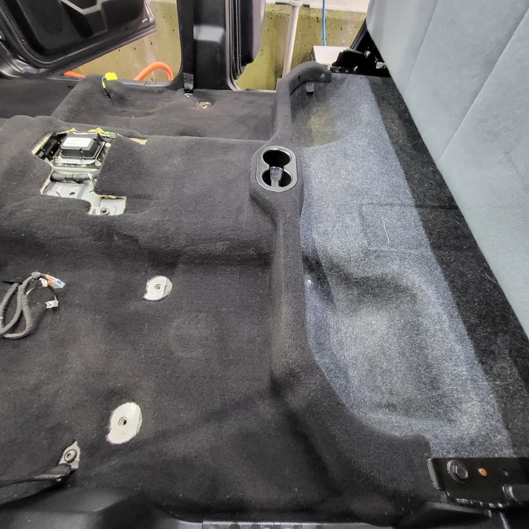 A black carpeted floor of a car with a hole in the middle