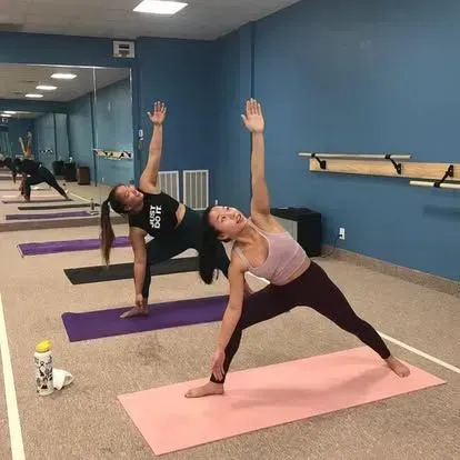 Two people practicing yoga in a blue studio