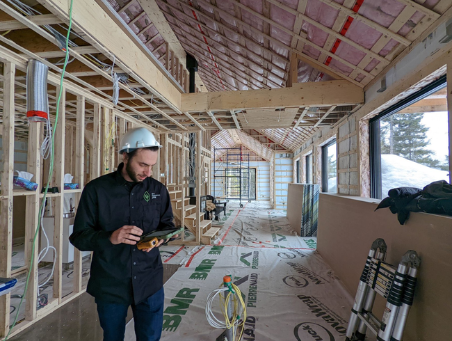 Ouvrier du bâtiment portant un casque de chantier utilisant une tablette à l'intérieur de la structure d'un bâtiment.