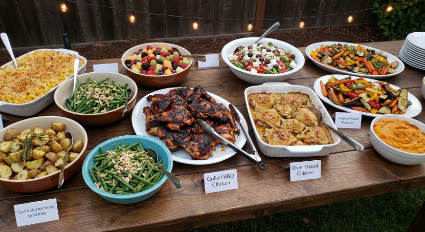 Buffet table with assorted dishes, including salads, roasted meats, and bread, on wooden serving platters