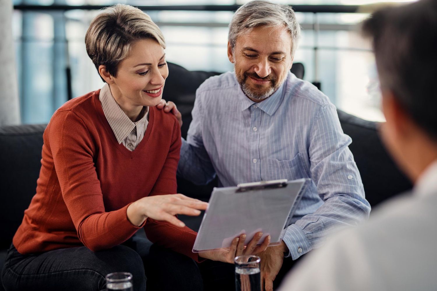 Two people smiling and reviewing a tablet together in an office setting