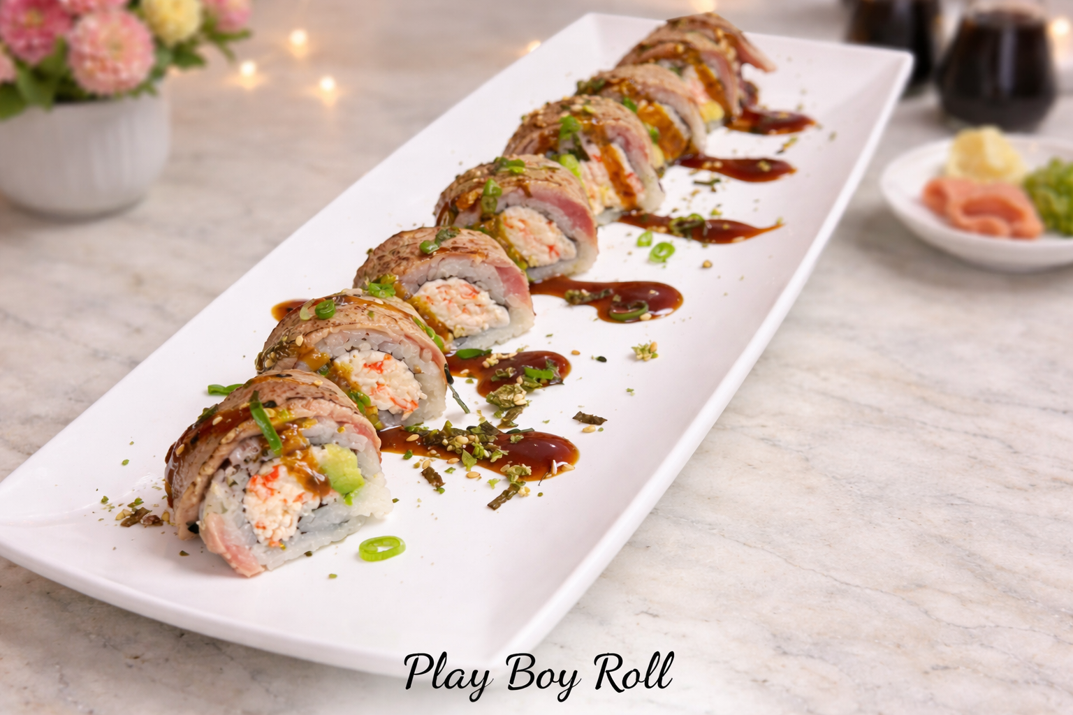 Sushi roll sliced on a white platter with dark sauce drizzles and wasabi on a marble table