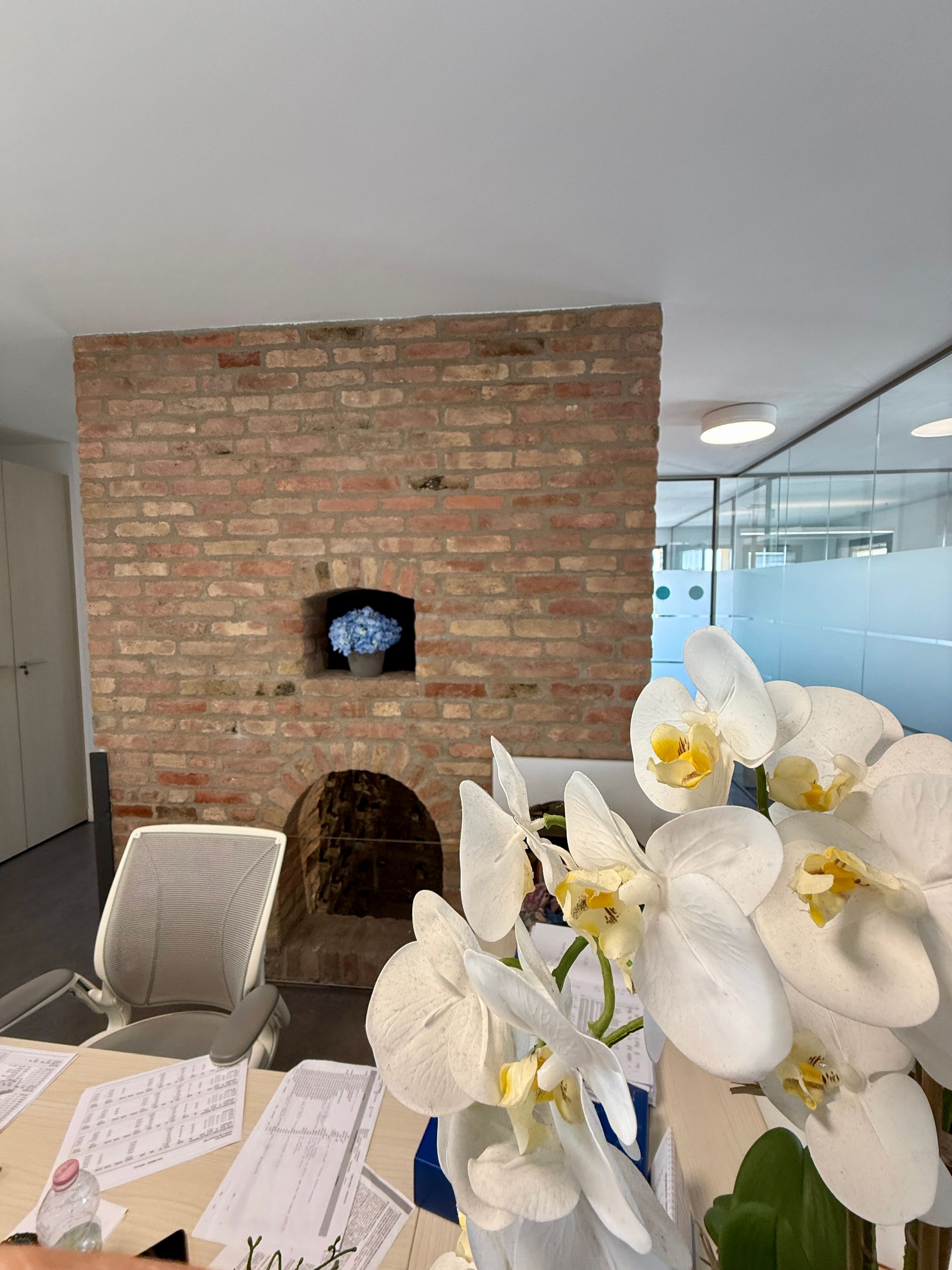 Una stanza con un muro di mattoni e fiori davanti