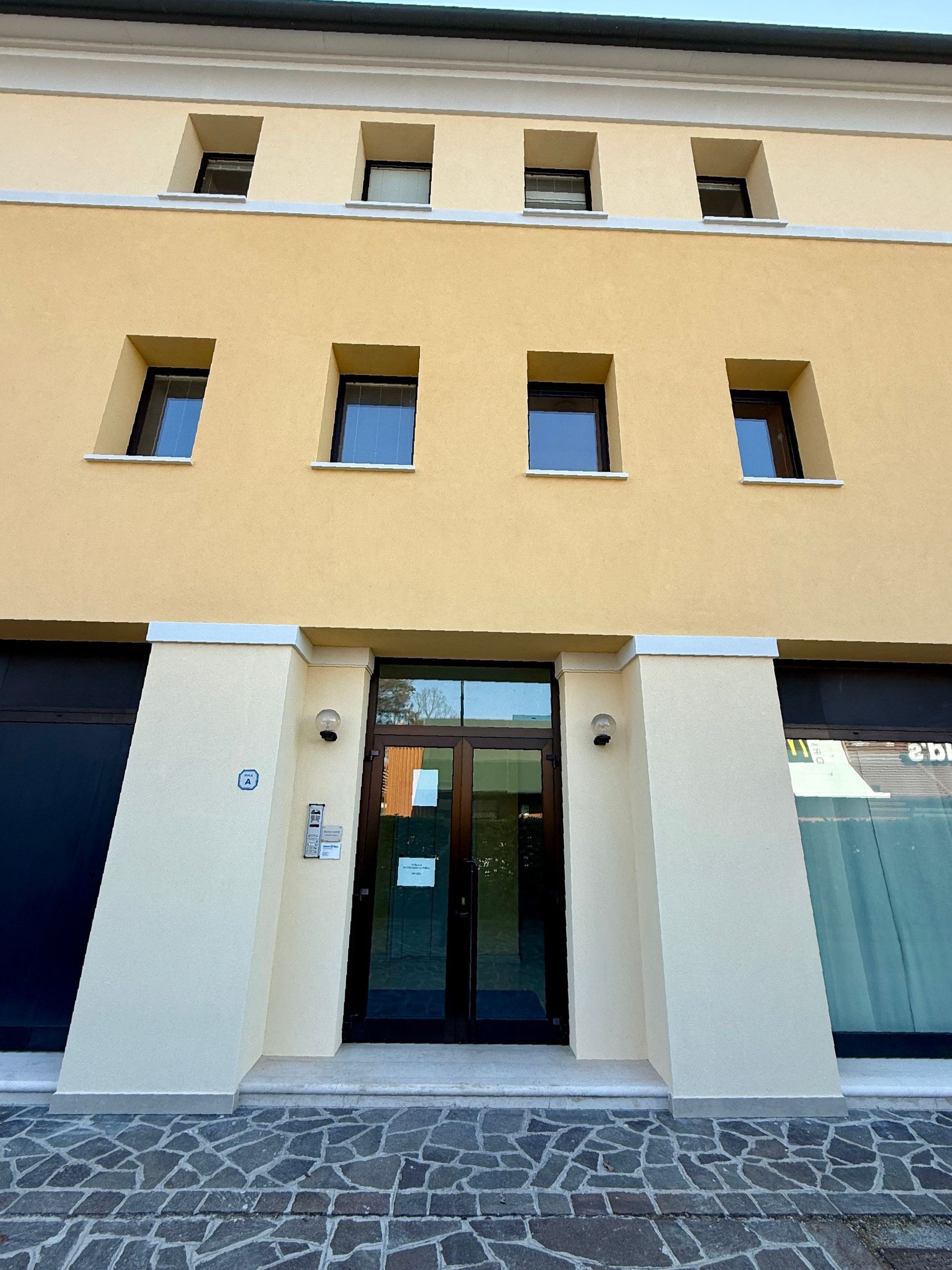Un edificio giallo con una porta e finestre nere