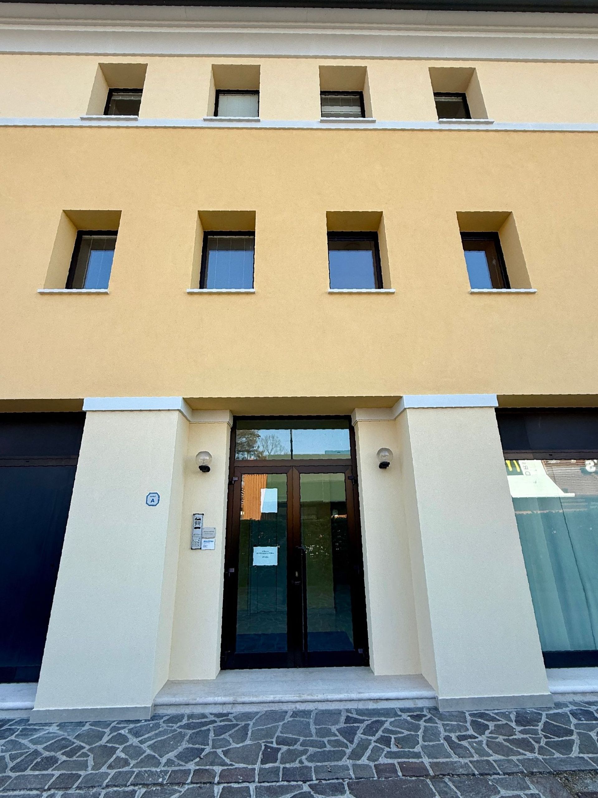 Un edificio giallo con una porta e finestre nere