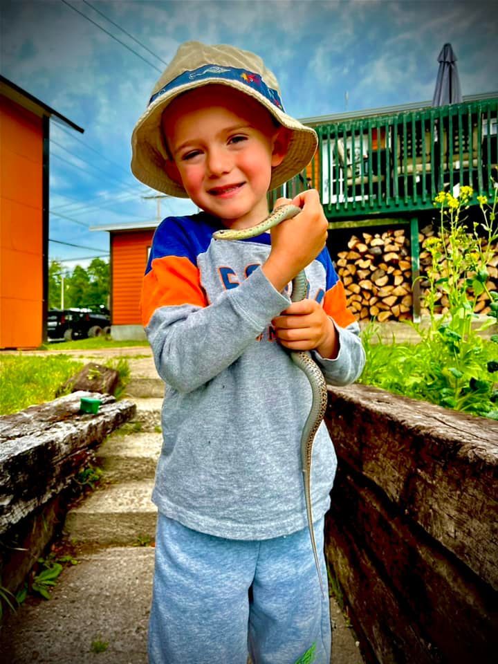 Un jeune garçon portant un chapeau tient un serpent dans ses mains.