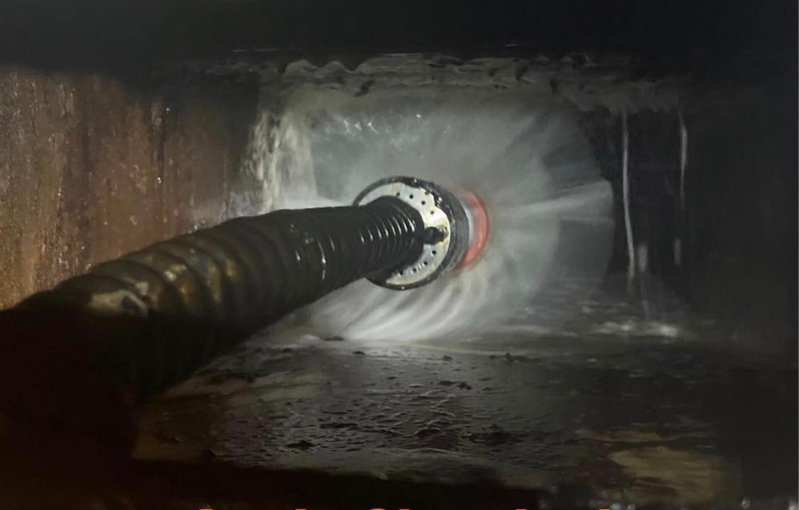 Un tuyau est utilisé pour nettoyer un drain dans une pièce sombre.